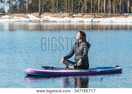 Calm Beauty Woman Sit On The Sup Board In The Middle Of Lake. Female Reclining On Stand Up Paddle Bo