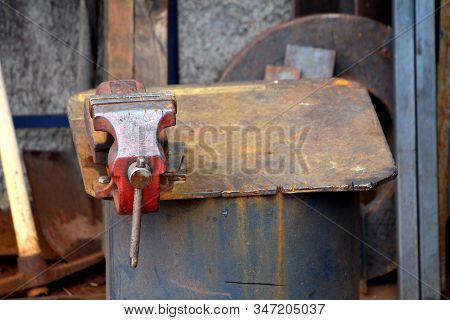 Old Rusted Workbench Vice Mounted On Leaning Makeshift Improvised Metal Table Surrounded With Tools 