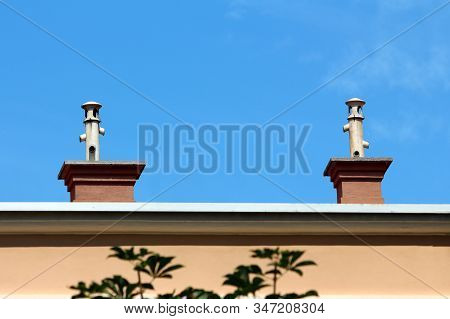 Two Chimneys With Unusual Pipes On Top With Multiple Openings And Protective Caps Built On Top Of Su