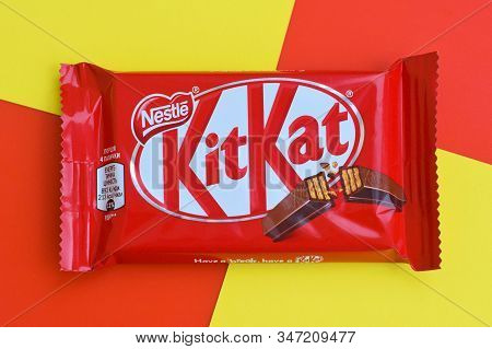 Kit Kat Chocolate Bars In Red Wrapping Lies On Yellow And Red Background. Kit Kat Created By Rowntre