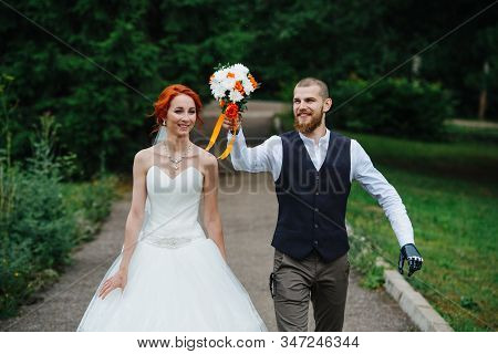 Exited Newly Wed Couple Walking Down The Path Through A Park