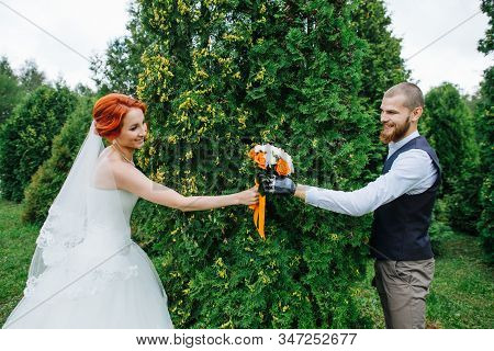 Newly Wed Couple Exchanging Bouquet, Posing For A Photo In A Juniper Park