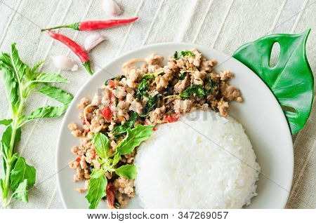 Rice Topped With Stir-fried Pork And Basil In Dish On Tablecloth.