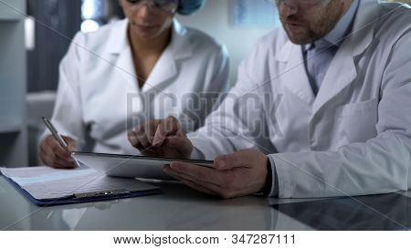 Scientist Working On Tablet And Female Assistant Making Notes, Clinic Teamwork