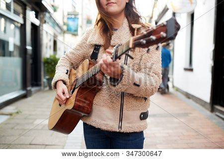 Close Up Of  Female Musician Busking Playing Acoustic Guitar  Outdoors In Street