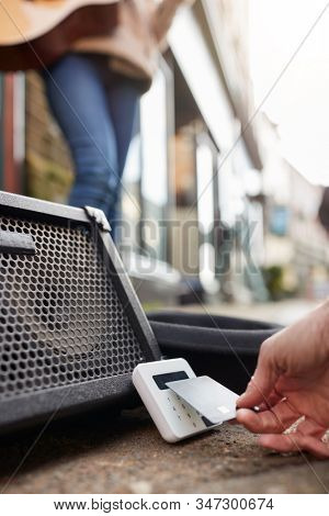 Close Up Of Person Using Contactless Payment Machine At Feet Of Female Musician Busking In Street