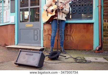 Close Up Of Female Musician Busking Playing Acoustic Guitar Outdoors In Street