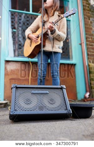 Close Up Of Female Musician Busking Playing Acoustic Guitar Outdoors In Street