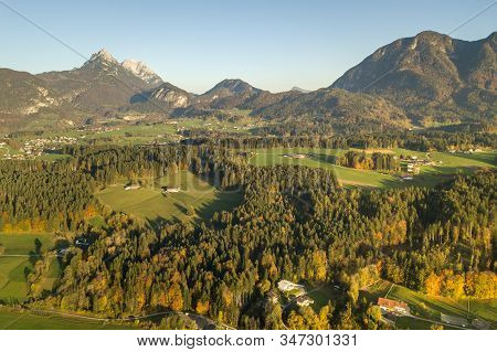 Aerial View Of Green Meadows With Villages And Forest In Austrian Alps Mountains.
