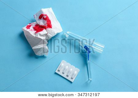 Anoscope, Suppositories And Toilet Paper With Blood On Light Blue Background, Flat Lay. Hemorrhoid T