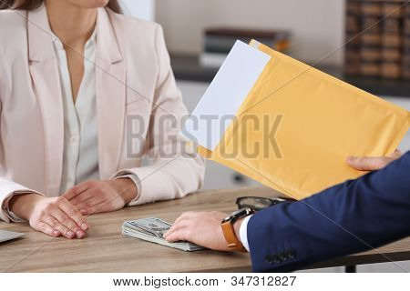 Man Offering Bribe To Woman At Table In Office, Closeup