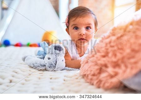 Beautiful infant happy at kindergarten around colorful toys lying on blacket