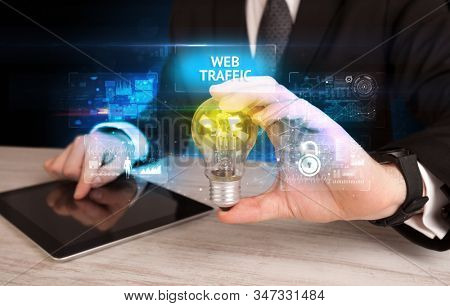 Businessman holding lightbulb with WEB TRAFFIC inscription, online security idea concept