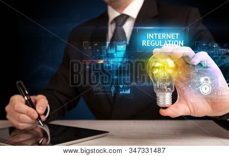 Businessman holding lightbulb with INTERNET REGULATION inscription, online security idea concept