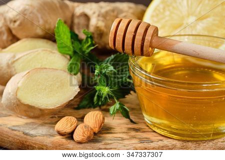 Honey With Ginger, Lemon And Mint And Nuts On Wooden Board And Grey Background.