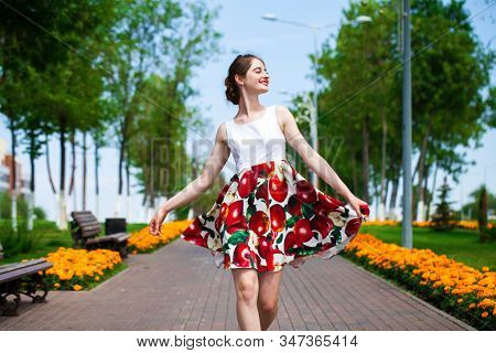 Close up, Young beautiful brunette girl in summer dress walks in the park
