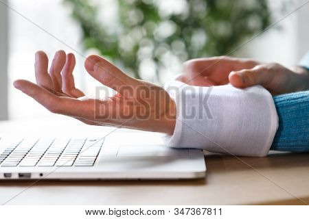 Close Up Of Man Applying Cold Compress To A His Painful Wrist Caused By Prolonged Work On The Comput