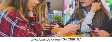 Group Of Friends Hanging Out With Each Other Sitting In A Bar Using Their Mobile Phones - Young Peop