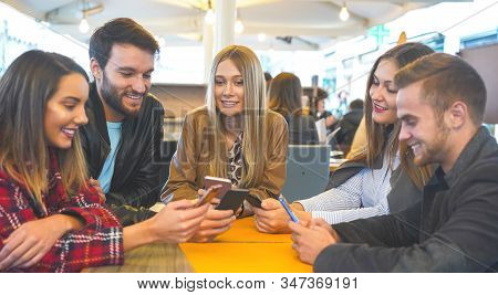 Group Of Friends Hanging Out With Each Other Sitting In A Bar Using Their Mobile Phones - Young Peop