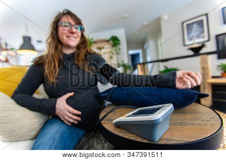 A Selective Focus Shot Of Lady Having A Prenatal Health Check, Sitting On Sofa With A Sphygmomanomet