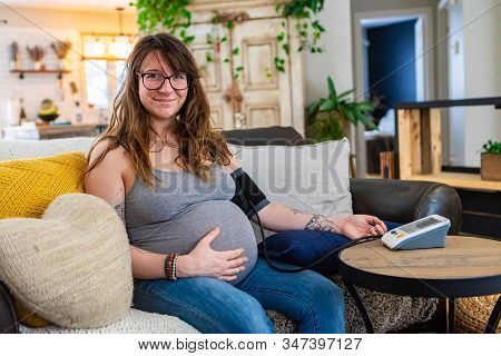 A Beautiful Young Pregnant Woman Carries Out Prenatal Health Checks At Home Using A Digital Sphygmom
