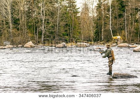 Man Fly Fishing In A Stormy River With Fishing Rod