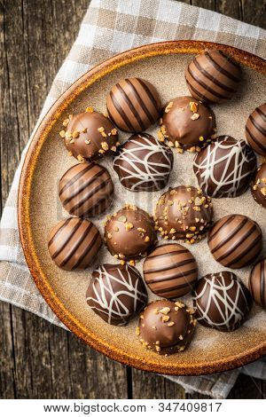 Praline bonbons. Chocolate truffles on plate on old wooden table. Top view.