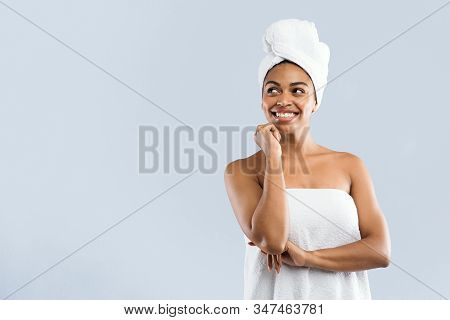 Cool Offer In Spa. Excited Young African Woman Wrapped In White Bath Towels Looking At Copy Space, G