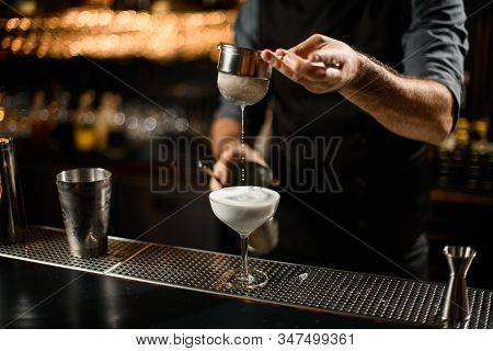 Bartender Mixes The Alcohol Drink And Uses A Sieve