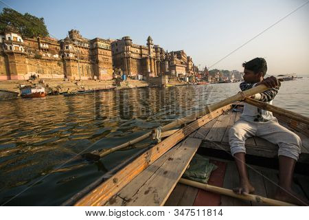 VARANASI, INDIA - MAR 26, 2018: Boatmen on a boat glides through water on Ganges river along shore of Varanasi. According to legends, the city was founded by God Shiva about 5000 years ago.
