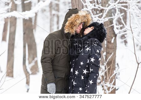 Young Love Couplekissing In A Snowy Park. Winter Season.