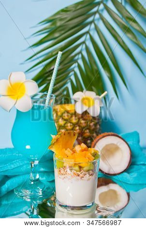 Exotic Tropical Fruit Salad With Muesli And Yogurt In A Glass With Pineapple, Coconut And Blue Cockt