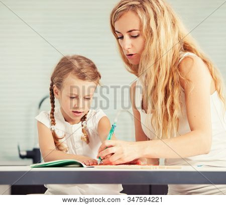 Parent teaches a child to write. Mom helping her daughter do homework