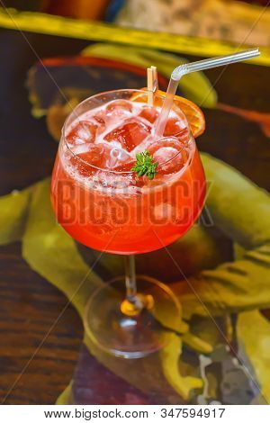 Cocktail With Dried Lemon, Raspberries And Ice On The Bar. Bright Red Cocktail With Foam
