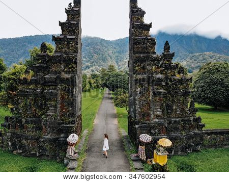 Tourist Woman Walking Through Traditional Balinese Hindu Gate Candi Bentar Close To Bedugul, Bratan 
