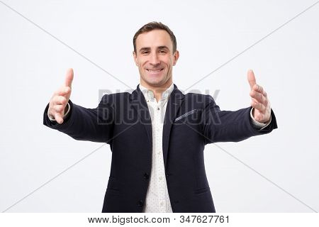 Overjoyed Happy Man In Suit Standing With His Hands Wide Open Welcoming His Parners Or Friends.