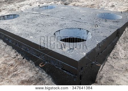 Manhole In The Concrete Block Painted With Black Coal Tar. Construction Site.