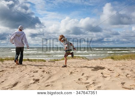 Brothers playing on the beach on a blustery spring day, focus on small boys face, some motion blur