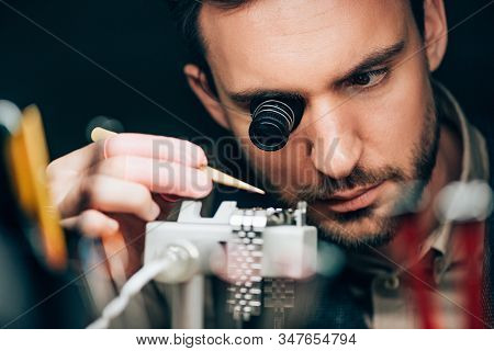 Selective Focus Of Watchmaker Working With Wristwatch On Timegrapher Movement Holder Isolated On Bla