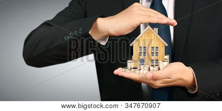 Growing Coins House On Stack Coins In Hand. Concept Of Investment Propert