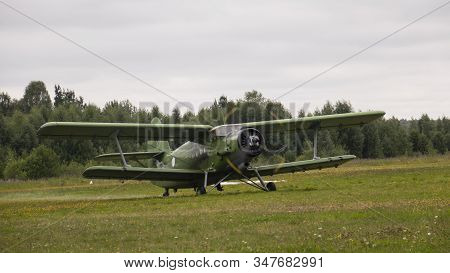 Agricultural Airplane Stands In A Field In The Green Grass.