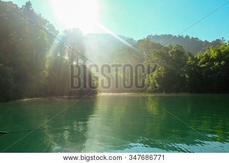 View In The Morning With Sunlight Shining Through The Trees As Light Beams. At Ratchaprapa Dam At Kh