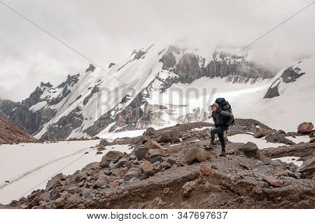Man Standing On The Rocks Around The Snow Remnants In The Mountains