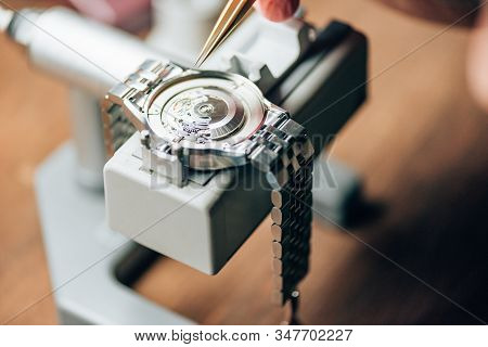 Cropped View Of Watchmaker Working With Tweezers And Wristwatches On Movement Holder