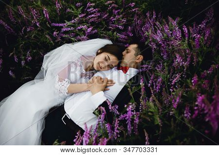 Couple At Sunset In A Wedding Dress Lie On The Grass With Lipin Flowers,festive Spring Wedding Photo