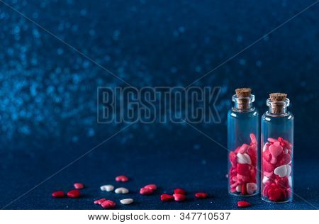 Two Glass Bottles With Heart-shaped Sugar Sprinkles On Gliter Blue Background. Valentines Day Concep