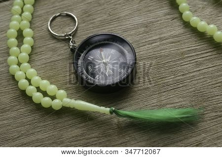Rosary Beads And Compass On Wooden Background.