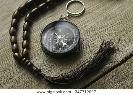 Rosary Beads And Compass On Wooden Background.