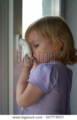 A Little Girl Standing In Front Of A Window
