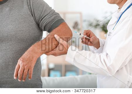 Doctor Giving Mature Man With Joint Pain Injection At Home, Closeup
